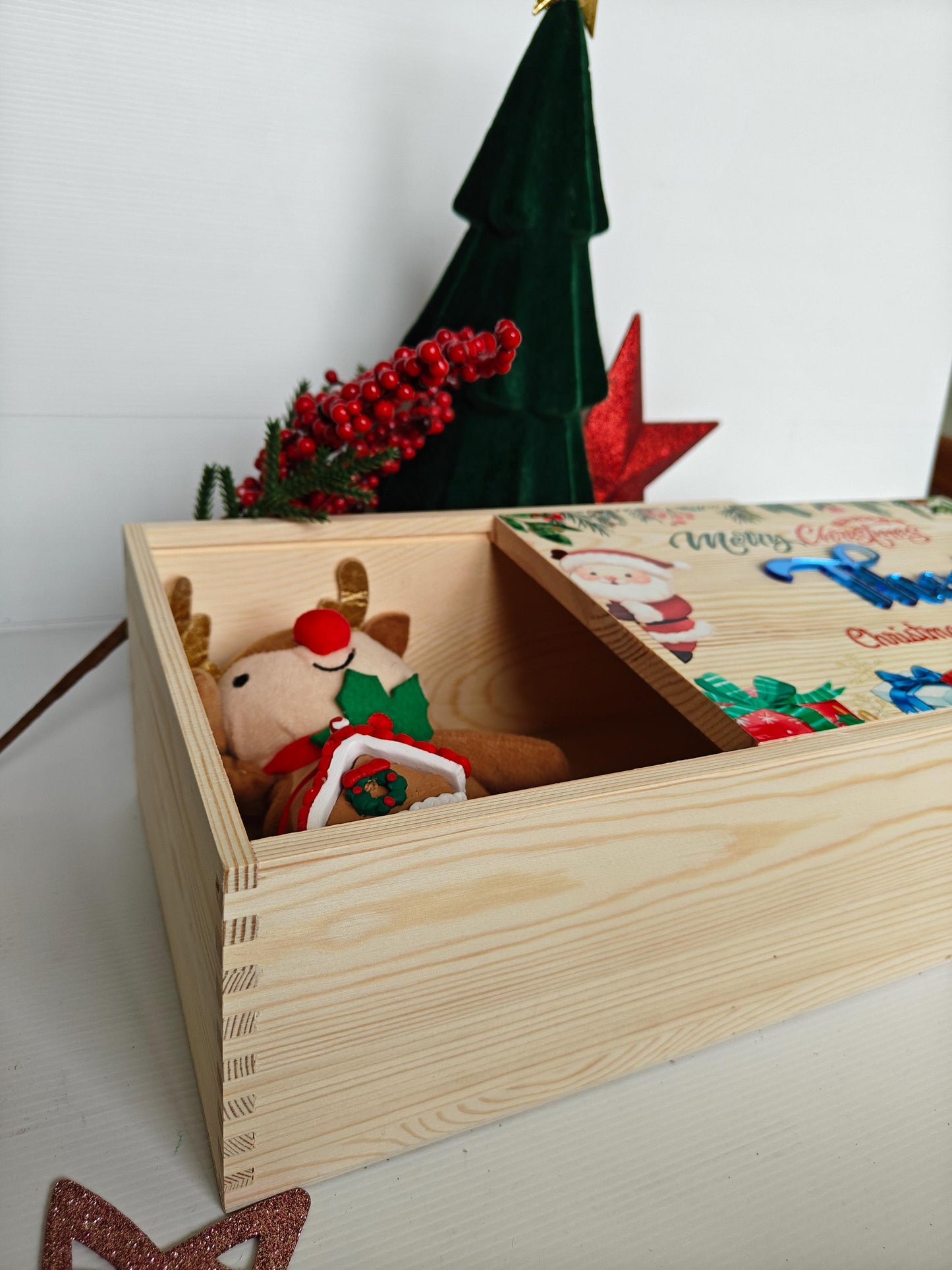 Wooden toy box with a plush reindeer toy inside, decorated with Christmas-themed items.