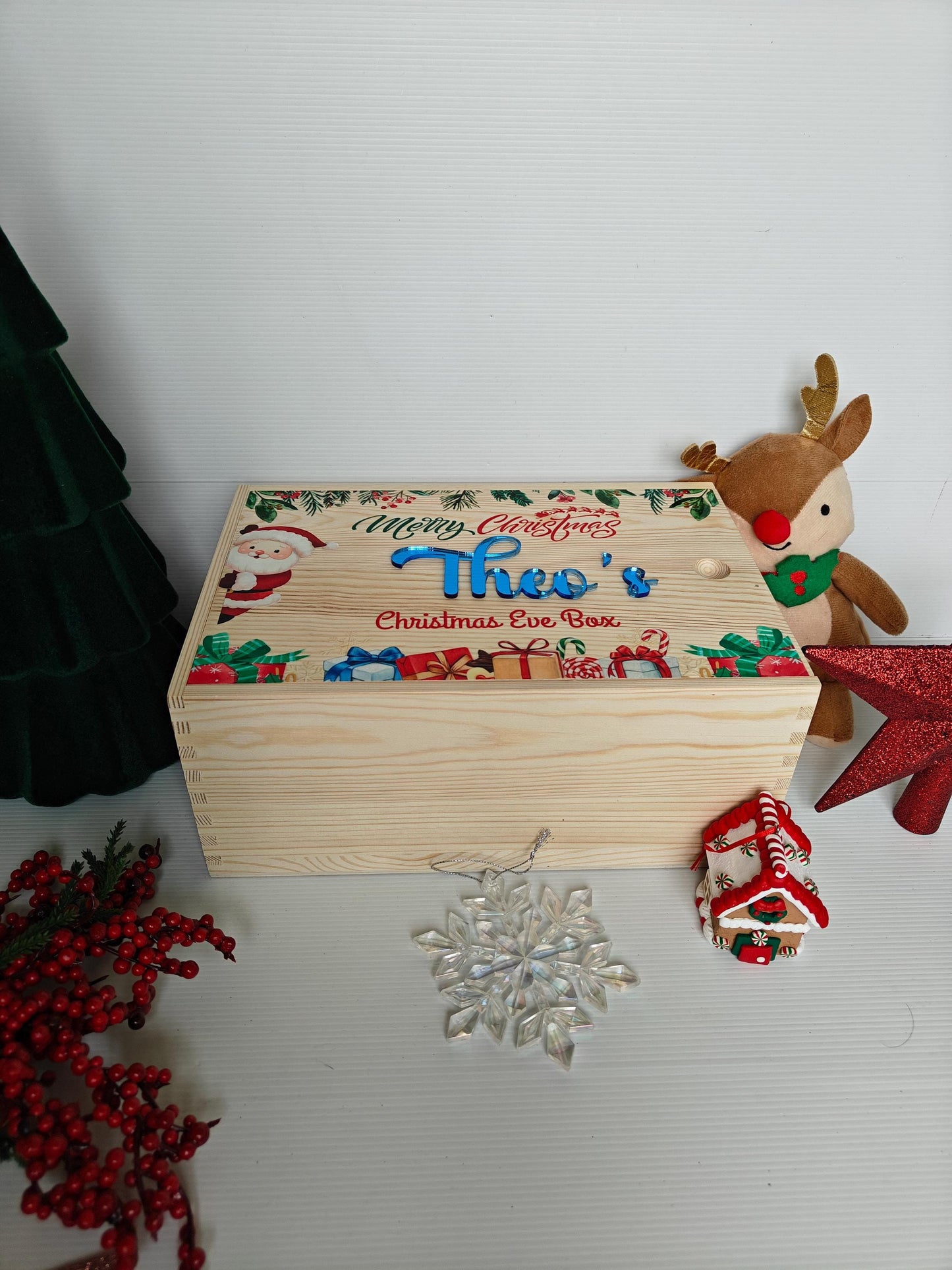 Decorative Christmas Eve box with festive design and reindeer toy on a white surface.