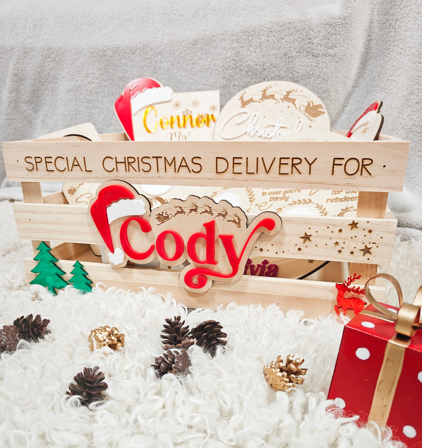 A wooden Christmas crate with cutout handles, personalised with the name 'Cody' in a bold, engraved font on the front.