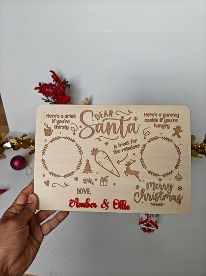 Wooden Christmas card with decorative text and illustrations held by a hand against a white background.