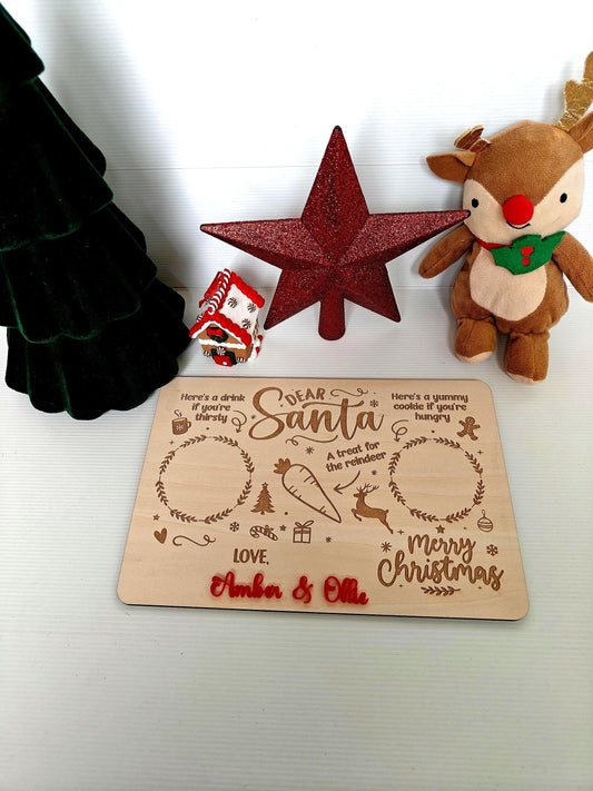 A personalised wooden board for Santa's treats, engraved with a child's name, with designated spaces for a drink, a snack, and a carrot for the reindeer.